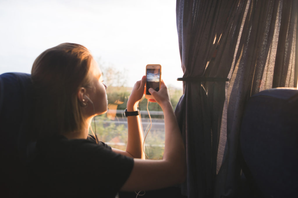 Tourist Woman Sits In A Bus Near The Window And Photographs Land